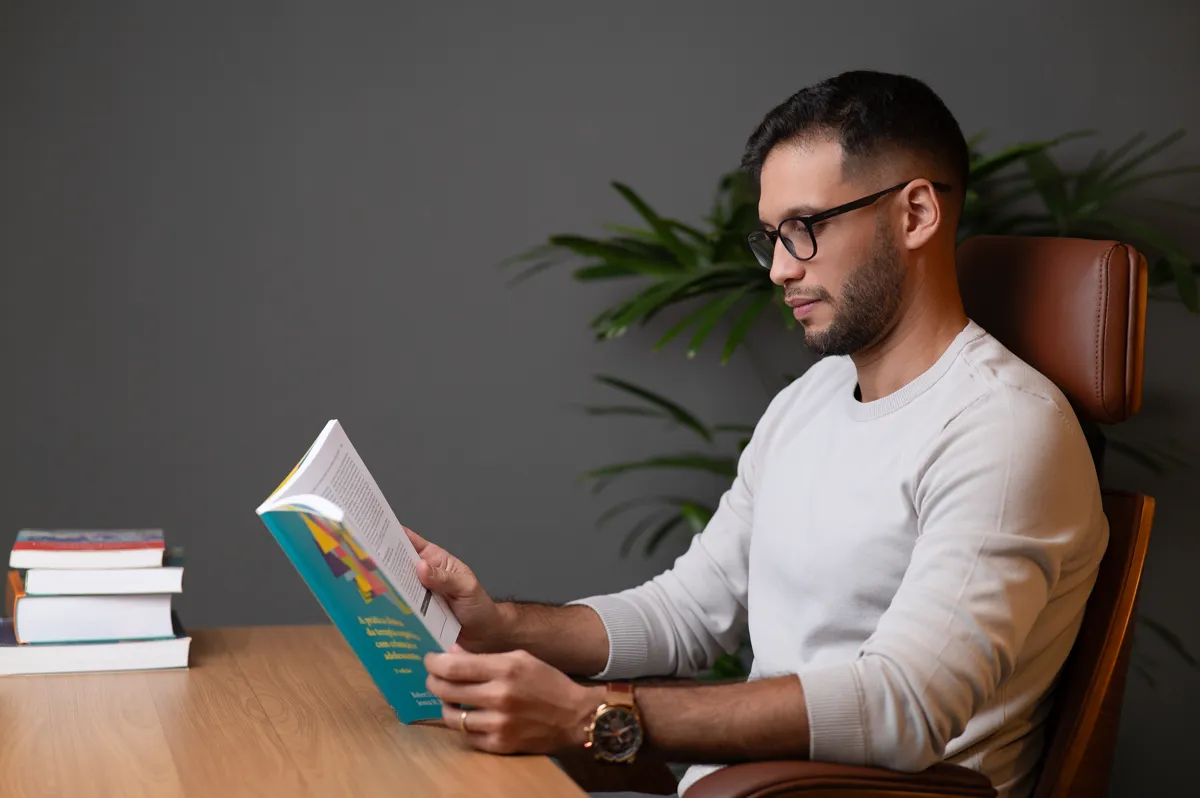 Henrique Costa lendo um livro de psicologia à mesa