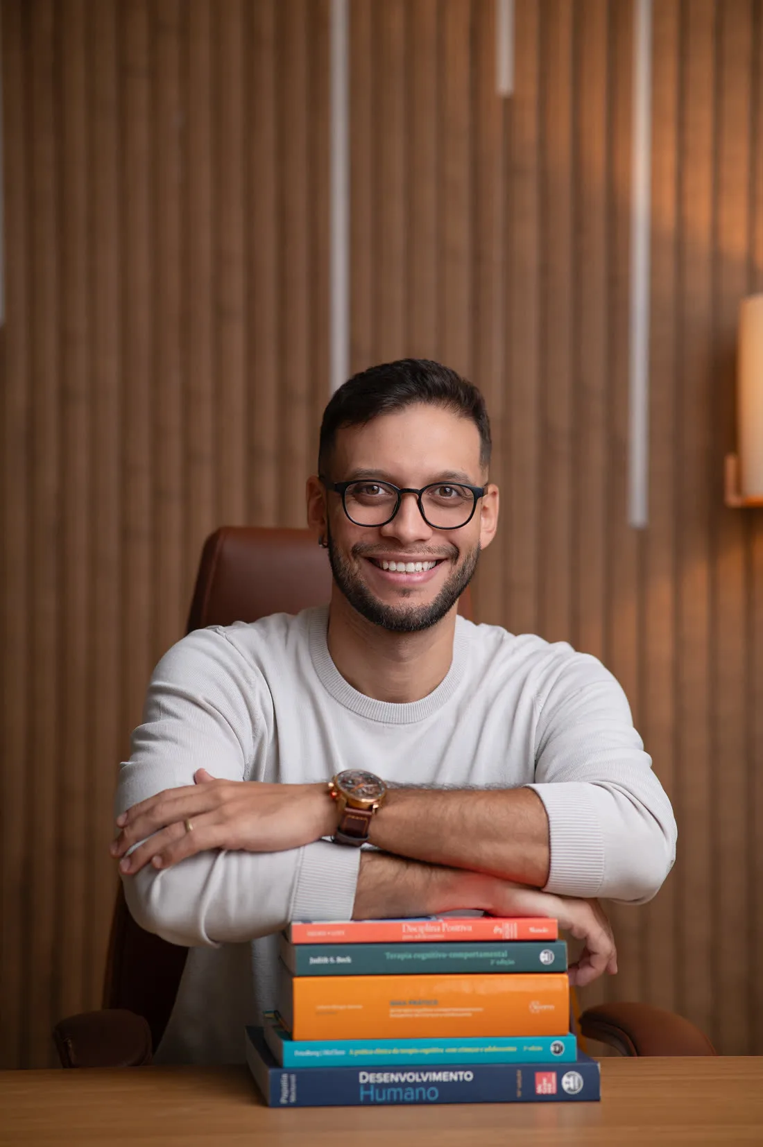 Henrique Costa com os braços apoiados sobre livros de psicologia